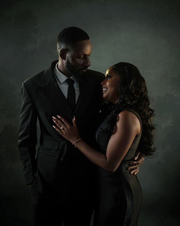 A couple in elegant black evening wear sharing a tender moment
